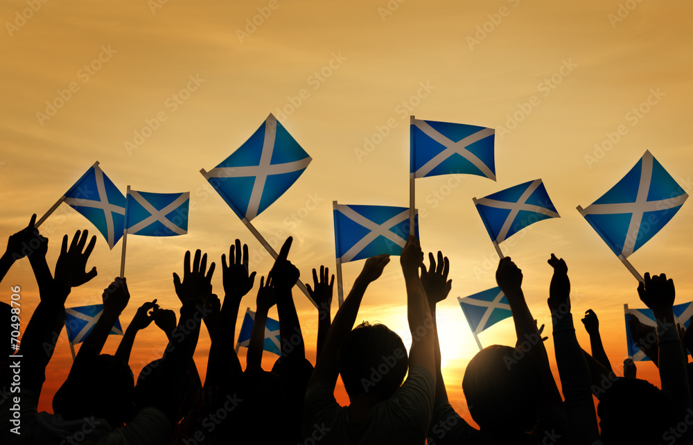 Group of People Waving Scottish Flags in Back Lit